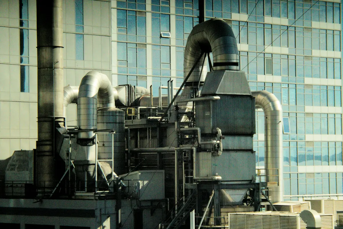 Equipo industrial con grandes tuberías junto a un edificio acristalado