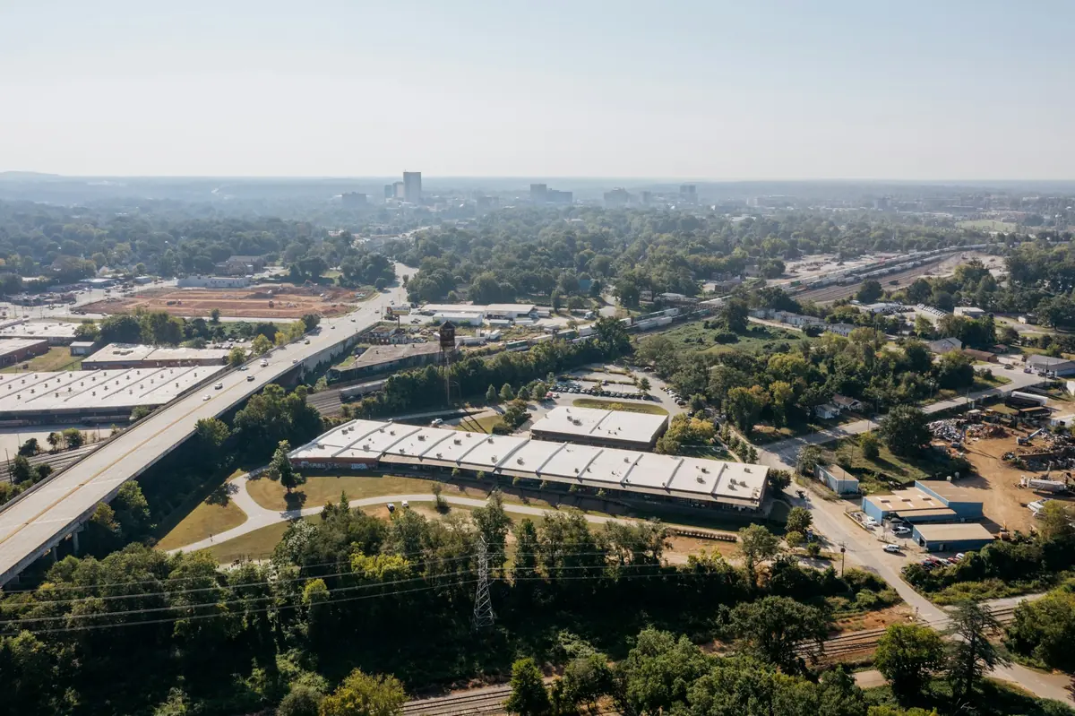 Vista aérea de naves industriales junto a una autovía rodeada de árboles