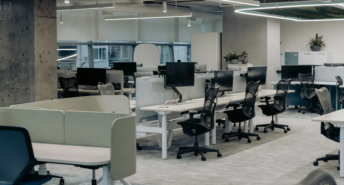 Oficina diáfana moderna con puestos de trabajo vacíos y mucha luz natural